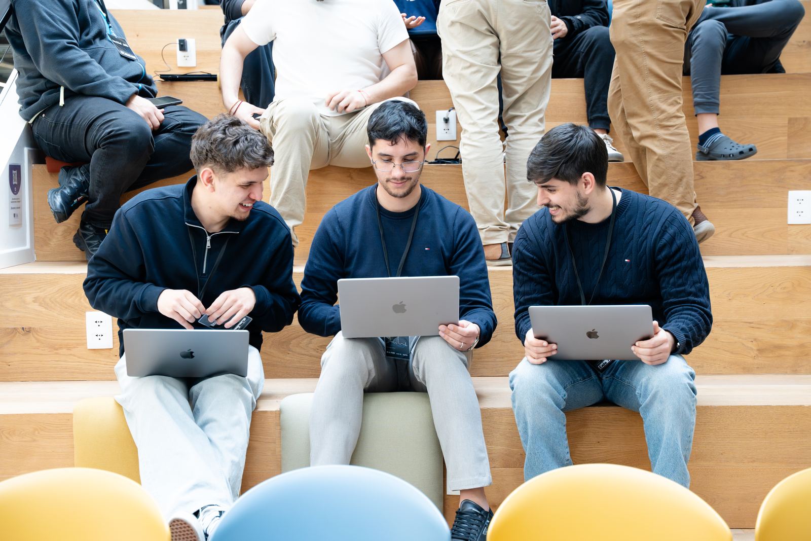 Tres participantes con sus laptops sentados en una escalera