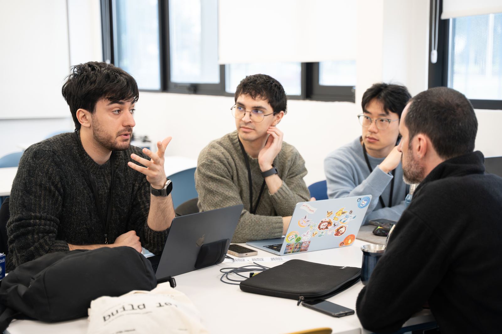 Equipo conversando alrededor de una mesa con laptops
